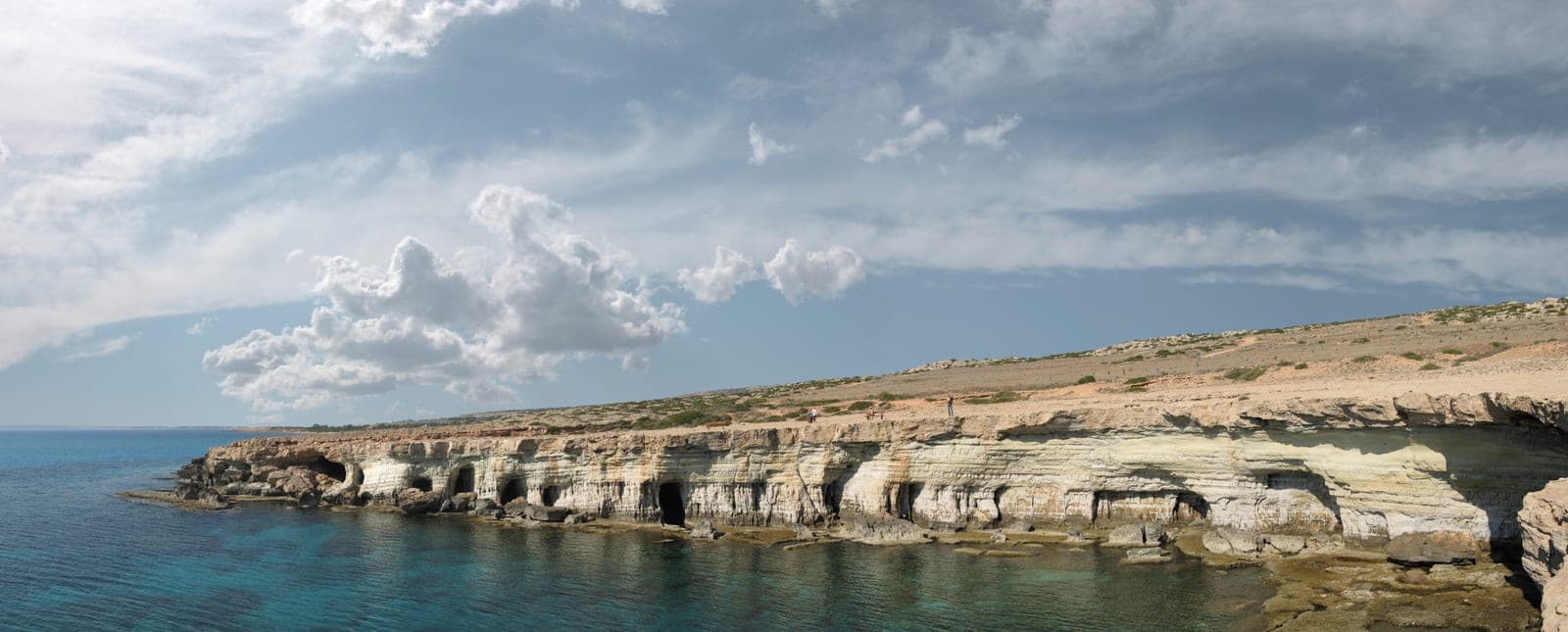 Cape Greco Caves Cyprus — Photo: Anna Anichkova | License: CC BY-SA 3.0 | Source: https://upload.wikimedia.org/wikipedia/commons/8/8b/Cape_Greco_2006_11_11_2197-2202_panorama.jpg